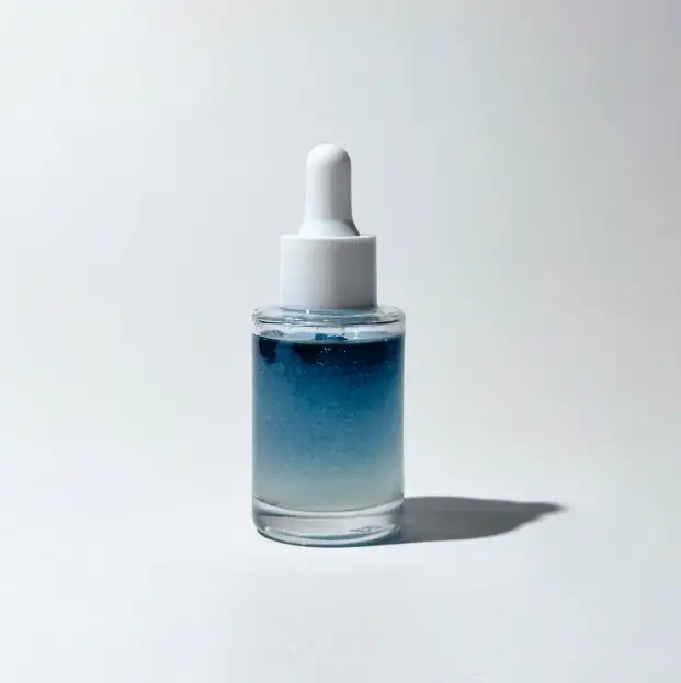 Glass dropper bottle with BY VALENTI blue bi-phase brightening serum on a light gray background