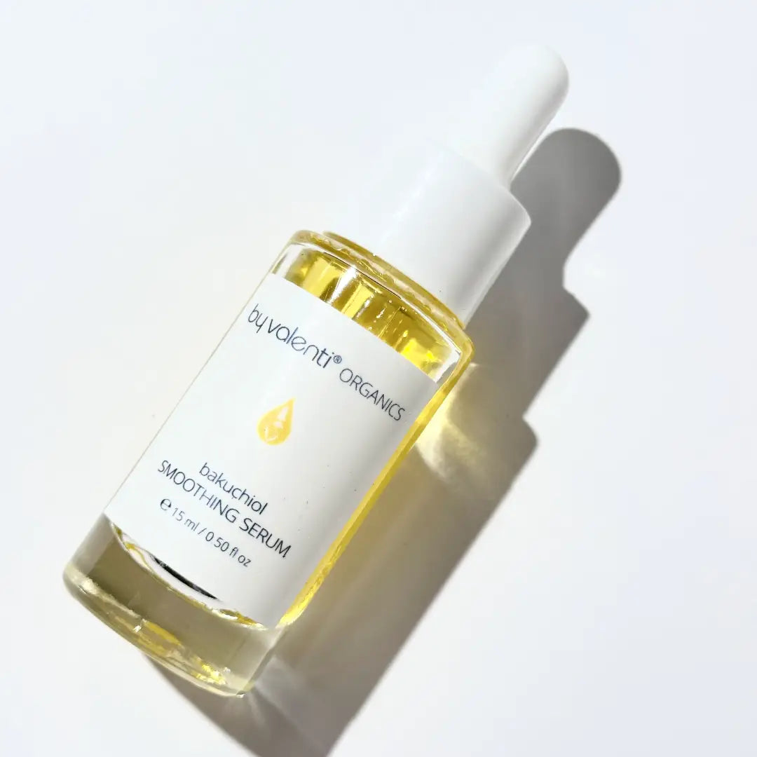 Bottle of golden By Valenti bakuchiol serum bottle with dropper on a light background