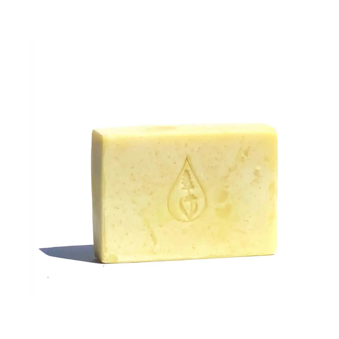 By Valenti soft yellow Chamomile bar of soap with company's stamped logo on a white background