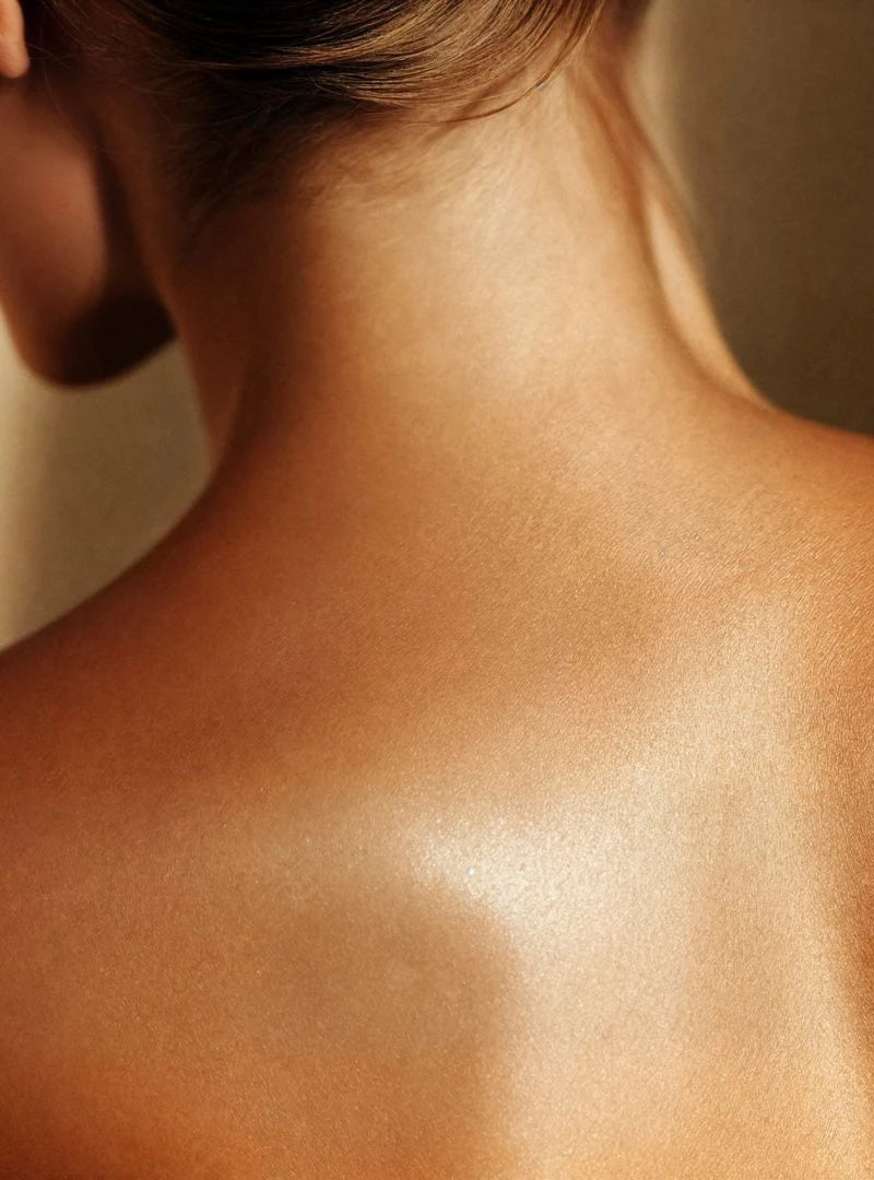 Woman naked back showing how skin shimmers after the application of By Valenti Estate a Barcola orange pink shimmering body oil