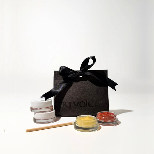 Beauty product set with jars and a black box labeled 'By Valenti' on a white background