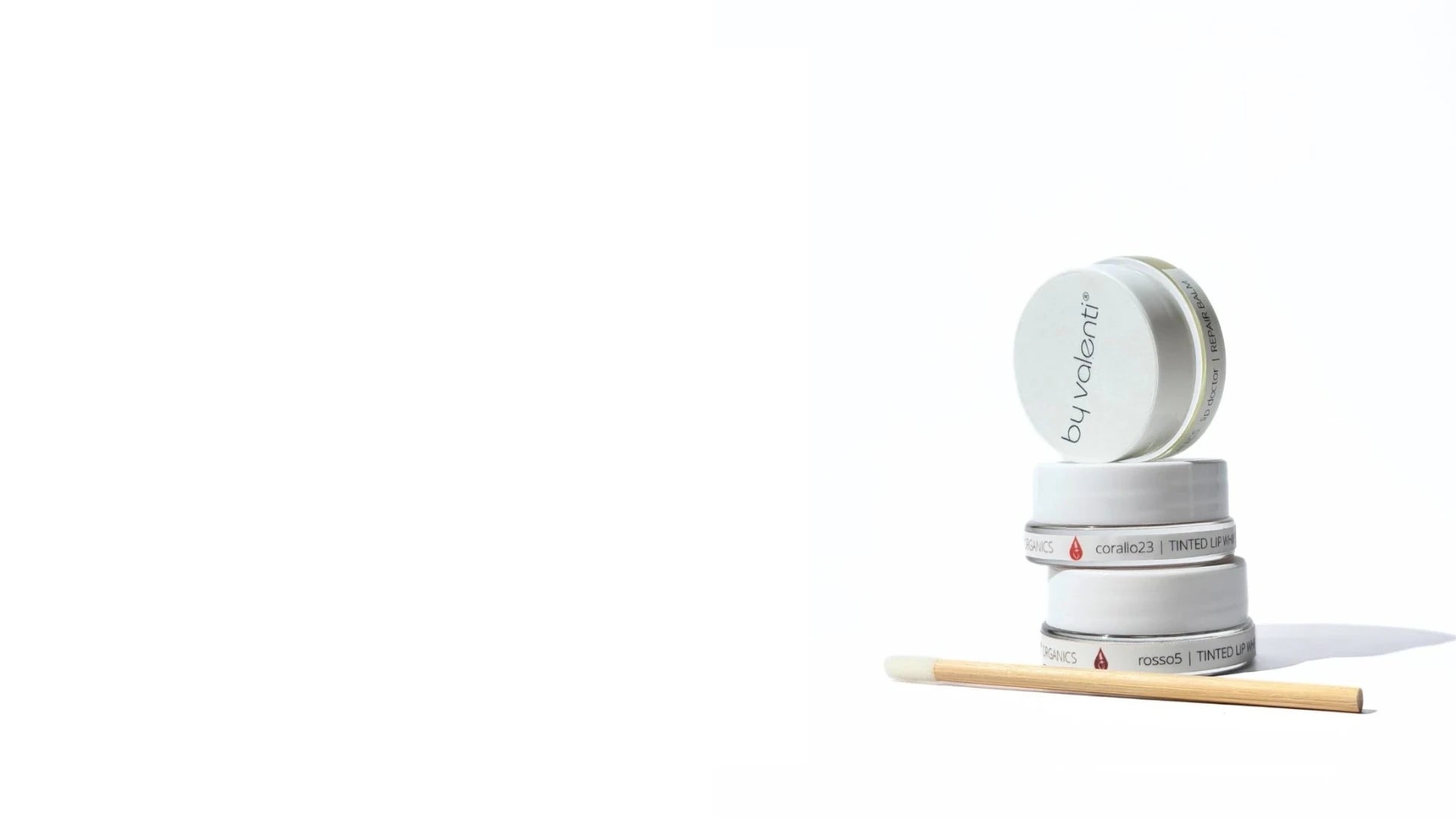 Stack of 3 jars of tinted lip whipped balms with an applicator wand on a white background